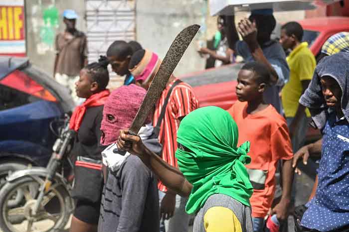 A man holds a machete during a demonstration against insecurity at Carrefour-Feuilles