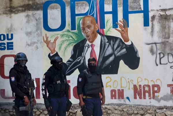 Police officers in front of a mural of Haiti's President Jovenel Moise after he was shot dead by gunmen in Port-au-Prince