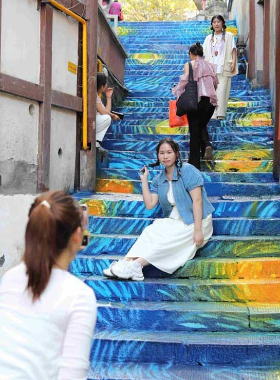 A tourist poses for a picture on a pathway in Ciqikou, a tourist attraction in southwest China's Chongqing municipality. 