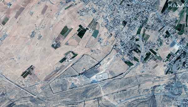 Handout satellite image taken and released by Maxar Technologies on February 26, 2021 shows the aftermath of recent U.S. airstrikes on buildings a crossing at the Syria-Iraq border near al-Qa’im, Iraq.  