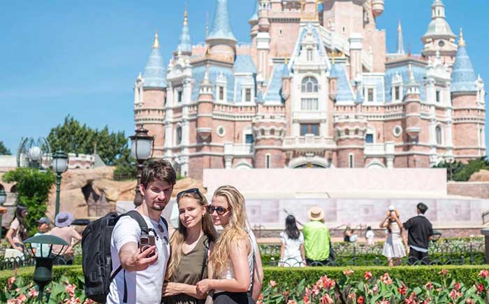 Foreign tourists pose for a picture at Shanghai Disney Resort. 