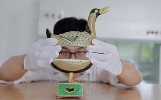 A staff member presents a restored "Ducktor Sui," a duck-shaped ceramic incense burner created in China's Ming Dynasty (1368-1644).