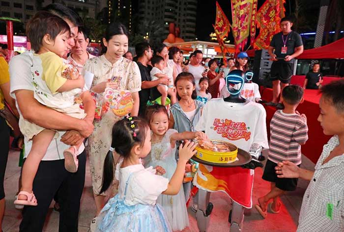 A service robot distributes mooncakes to pedestrians outside a shopping mall in Sanya, south China's Hainan province, Oct. 6, 2025.