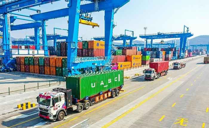 Unmanned trucks transport containers in an autonomous driving pilot zone of a container terminal.