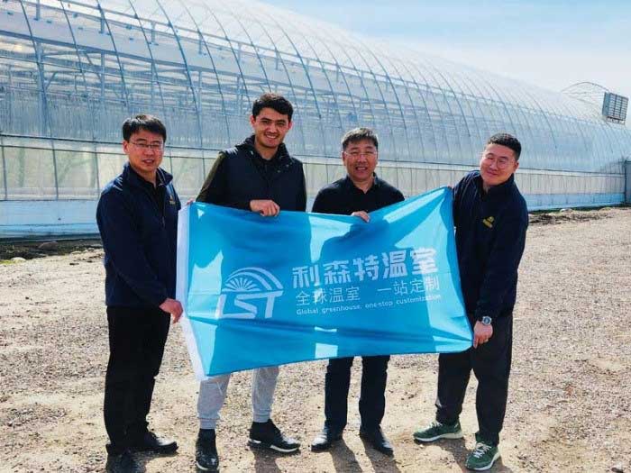 Chinese and Uzbek engineers pose for a picture in front of the greenhouses developed by Shandong Lisente Agricultural Technology Co., Ltd. (Lisente) in Uzbekistan.